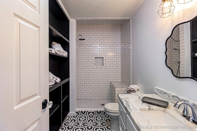 bathroom with tiled shower, tile patterned floors, vanity, and toilet