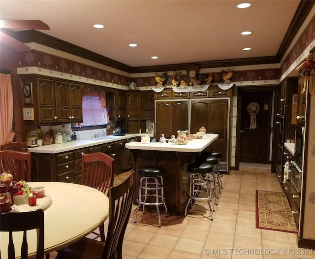 kitchen with dark brown cabinetry, paneled fridge, ornamental molding, and a kitchen island