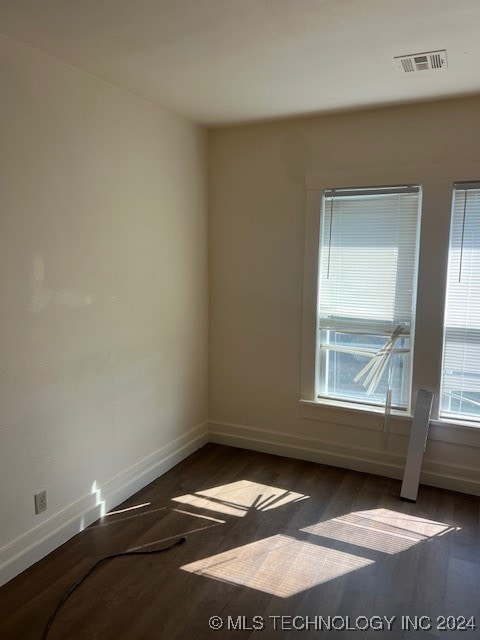 unfurnished room featuring plenty of natural light and dark hardwood / wood-style floors