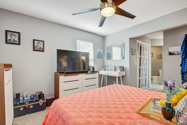 bedroom featuring light carpet, ensuite bathroom, and ceiling fan