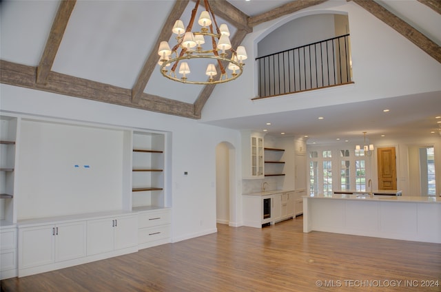 unfurnished living room featuring light hardwood / wood-style floors, beam ceiling, built in features, a chandelier, and high vaulted ceiling