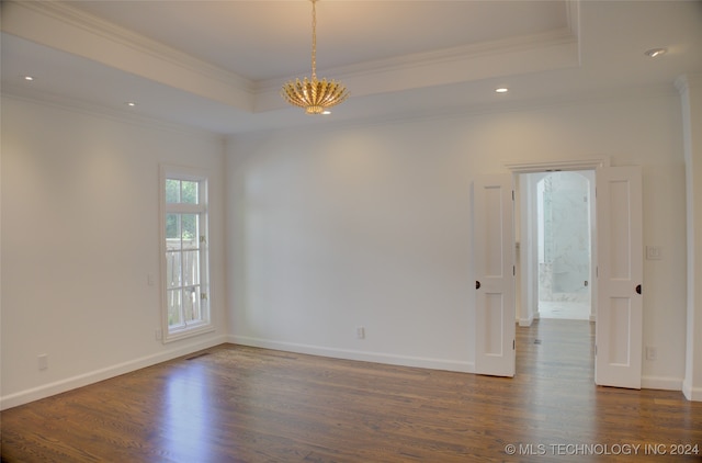 spare room with a chandelier, dark wood-type flooring, crown molding, and a tray ceiling