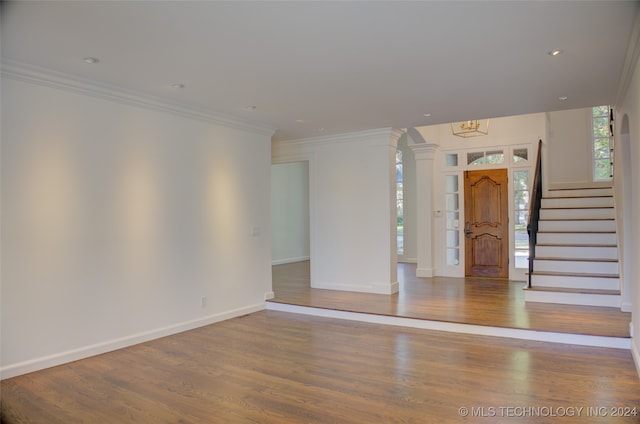 interior space featuring an inviting chandelier, crown molding, wood-type flooring, and plenty of natural light