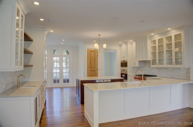 kitchen featuring kitchen peninsula, hanging light fixtures, dark hardwood / wood-style flooring, white cabinetry, and sink