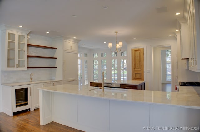 kitchen featuring kitchen peninsula, white cabinets, light stone countertops, and pendant lighting