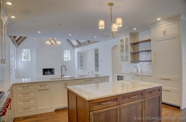 kitchen featuring vaulted ceiling with beams, a center island, hardwood / wood-style floors, and sink