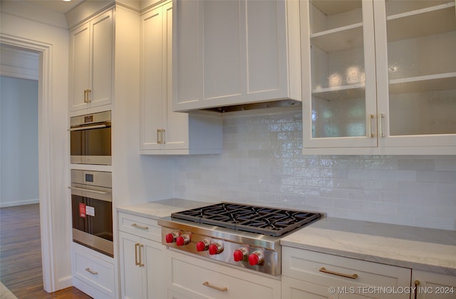 kitchen featuring white cabinets, stainless steel appliances, tasteful backsplash, and hardwood / wood-style floors