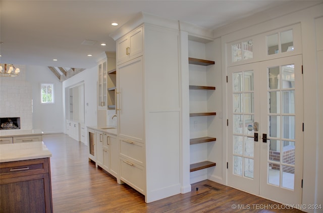 kitchen featuring sink, hardwood / wood-style floors, a notable chandelier, a brick fireplace, and built in features