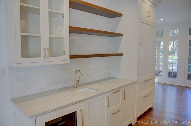 bar featuring dark hardwood / wood-style floors, sink, light stone countertops, white cabinets, and tasteful backsplash