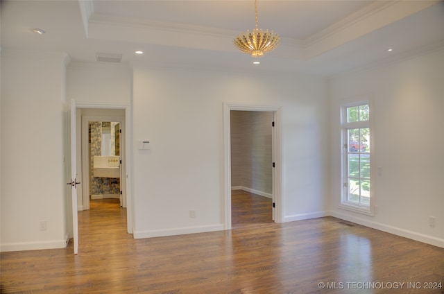 unfurnished room featuring ornamental molding, a tray ceiling, an inviting chandelier, and hardwood / wood-style floors