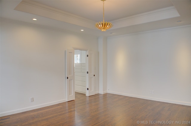 unfurnished room with crown molding, a tray ceiling, and dark hardwood / wood-style flooring