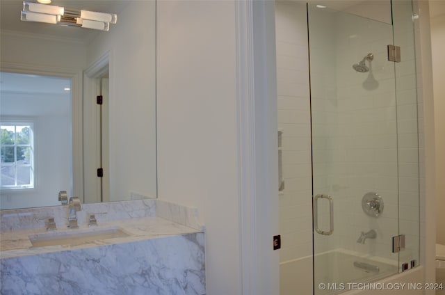 bathroom featuring sink, bath / shower combo with glass door, and crown molding