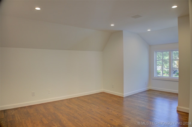 additional living space with dark wood-type flooring and vaulted ceiling