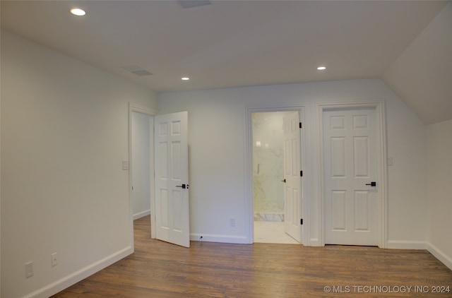 unfurnished bedroom featuring connected bathroom, lofted ceiling, and dark hardwood / wood-style flooring