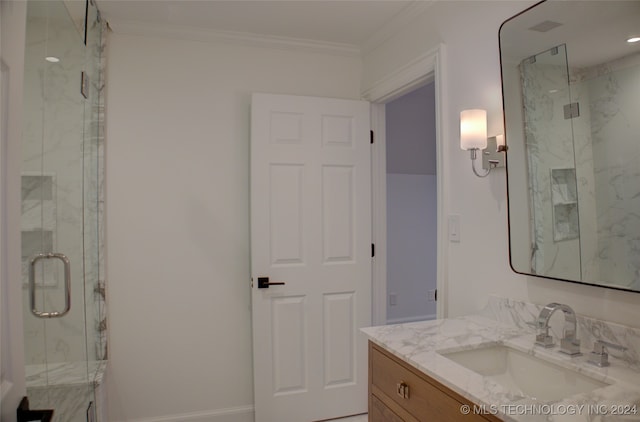 bathroom featuring vanity, ornamental molding, and a shower with door