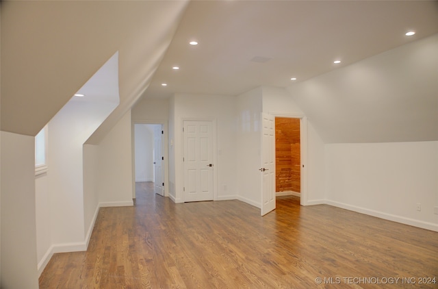 additional living space featuring wood-type flooring and lofted ceiling