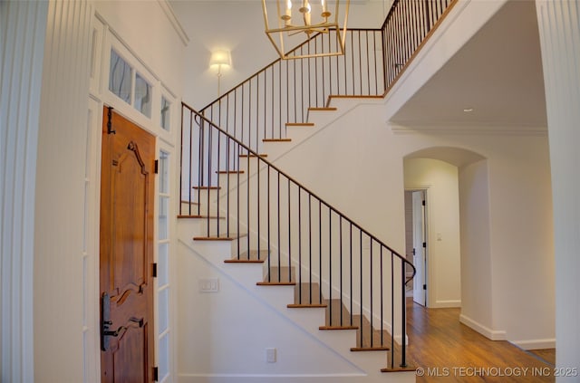 foyer entrance with a high ceiling, ornamental molding, and hardwood / wood-style floors