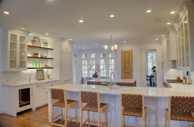 kitchen with wine cooler, white cabinets, a kitchen breakfast bar, hanging light fixtures, and kitchen peninsula