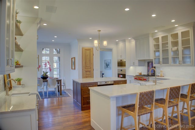 kitchen featuring sink, dark hardwood / wood-style floors, kitchen peninsula, pendant lighting, and white cabinets