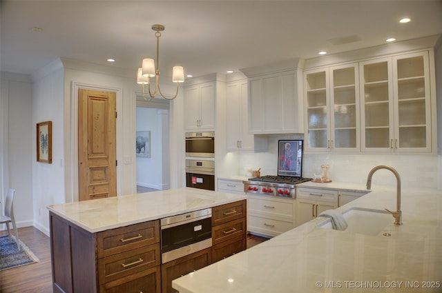 kitchen featuring white cabinetry, light stone countertops, decorative light fixtures, and stainless steel appliances