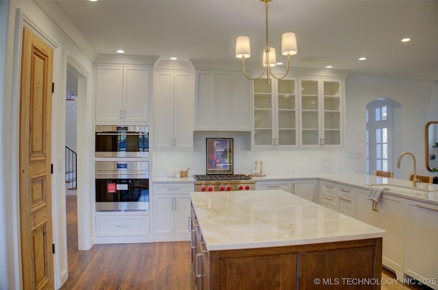 kitchen featuring white cabinetry, sink, stainless steel appliances, and hanging light fixtures