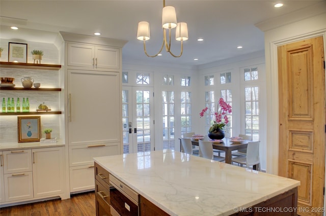 kitchen featuring hanging light fixtures, dark hardwood / wood-style floors, ornamental molding, light stone countertops, and white cabinets