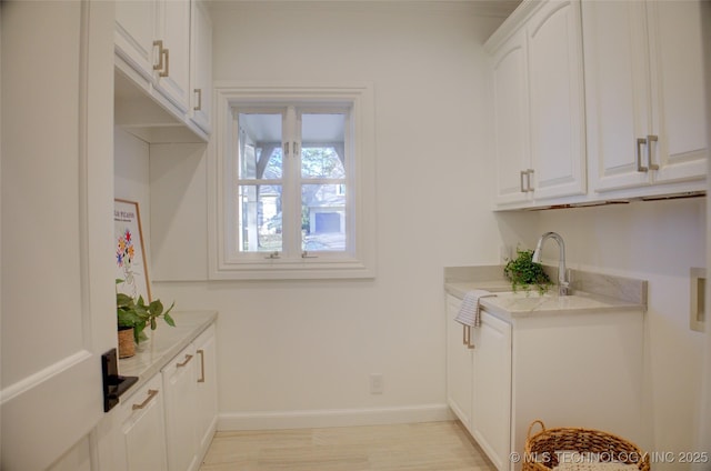 interior space with cabinets, sink, and light wood-type flooring