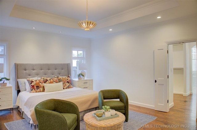 bedroom with a raised ceiling, crown molding, hardwood / wood-style flooring, and a notable chandelier