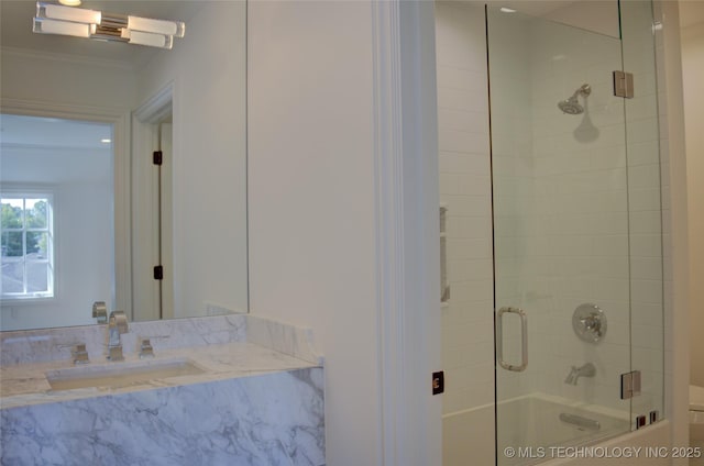 bathroom featuring enclosed tub / shower combo, ornamental molding, and sink