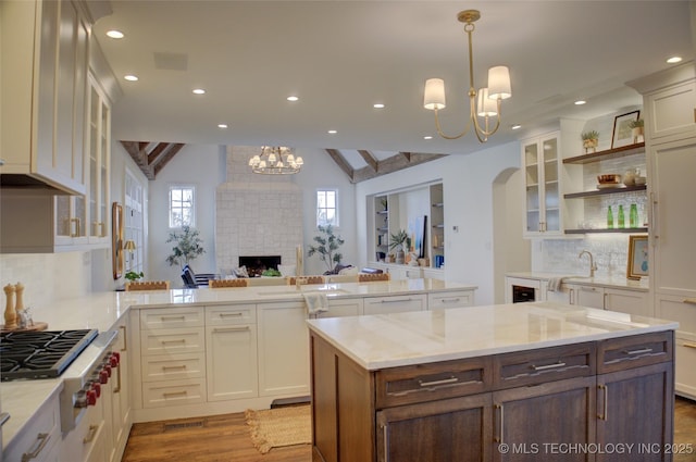 kitchen with an inviting chandelier, vaulted ceiling, stainless steel gas cooktop, and hanging light fixtures