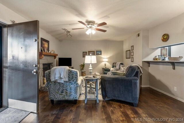 living room featuring dark wood-type flooring, a fireplace, and ceiling fan