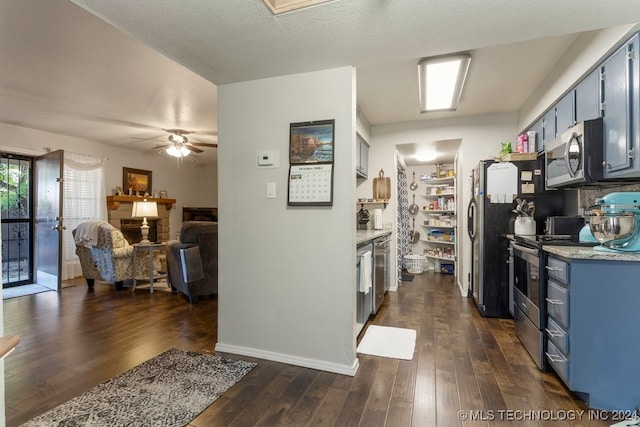 kitchen featuring blue cabinets, ceiling fan, stainless steel appliances, dark hardwood / wood-style floors, and a textured ceiling