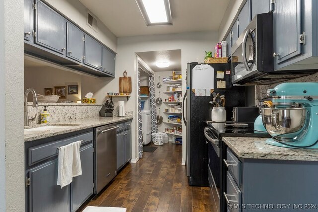 kitchen with dark wood-type flooring, appliances with stainless steel finishes, sink, and light stone counters