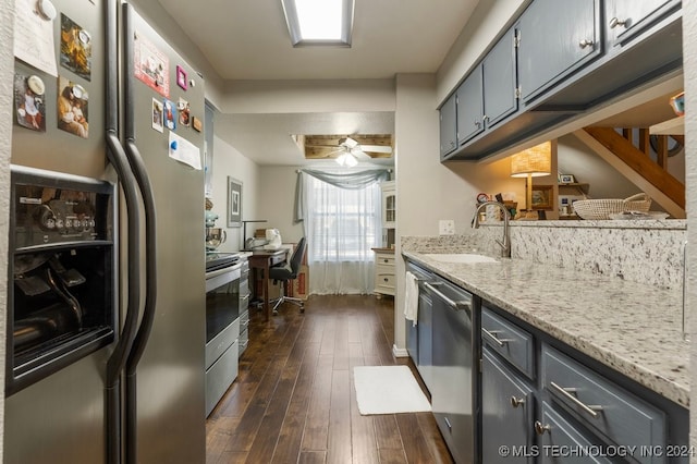 kitchen with ceiling fan, light stone counters, sink, dark wood-type flooring, and appliances with stainless steel finishes