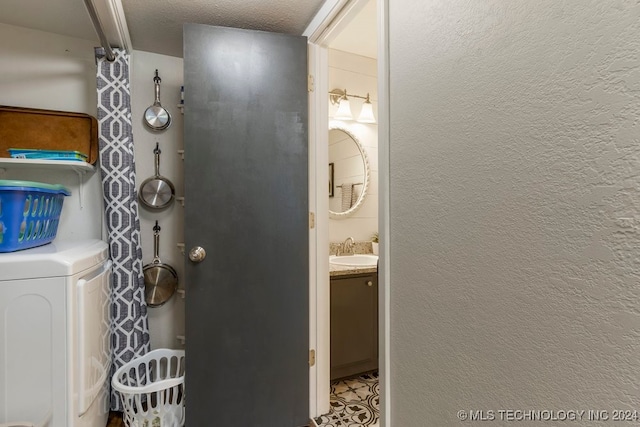 bathroom with washer / clothes dryer, vanity, and a textured ceiling