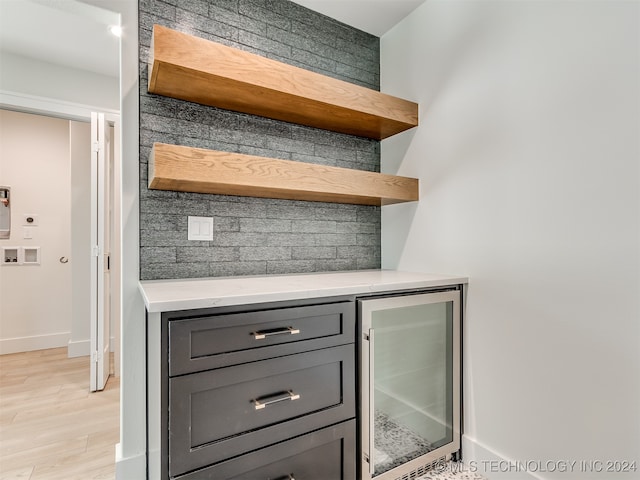 bar featuring gray cabinetry, light hardwood / wood-style floors, wine cooler, and tasteful backsplash