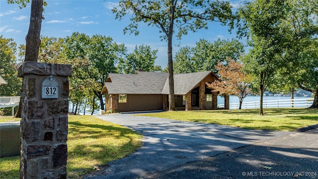 view of front of property featuring a water view, a front lawn, and a garage