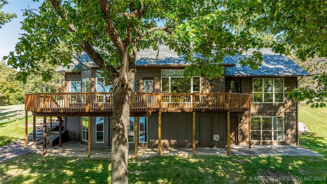 rear view of property featuring a wooden deck, a yard, and a patio