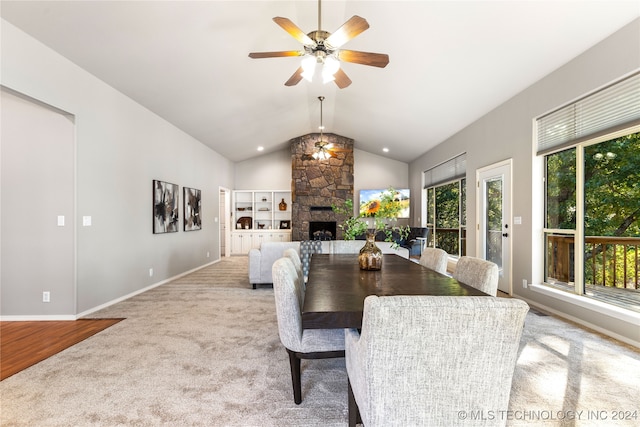 dining space featuring lofted ceiling, light carpet, a fireplace, and ceiling fan