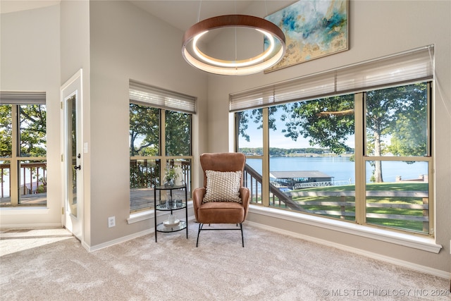 living area featuring light colored carpet, a water view, and a wealth of natural light