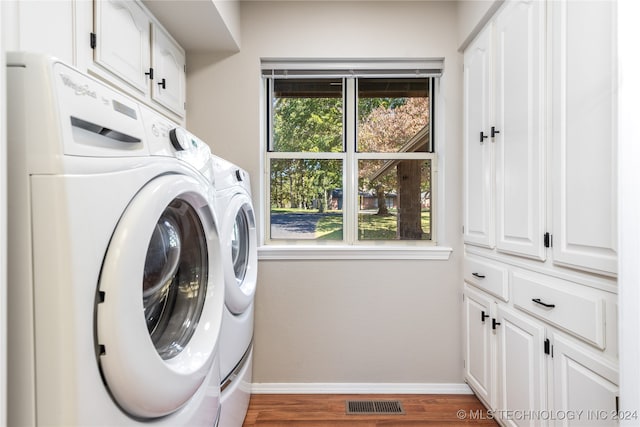 laundry room with dark wood-type flooring, independent washer and dryer, and cabinets