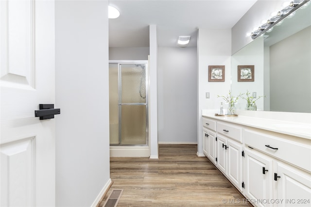 bathroom featuring vanity, hardwood / wood-style flooring, and a shower with door