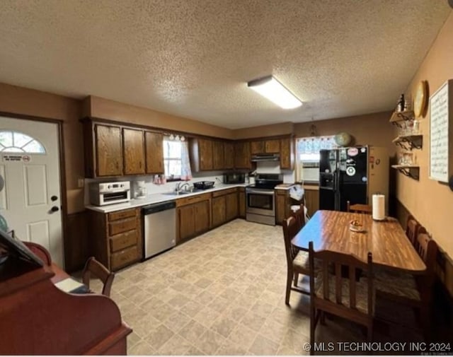 kitchen featuring a textured ceiling, sink, dark brown cabinetry, and stainless steel appliances