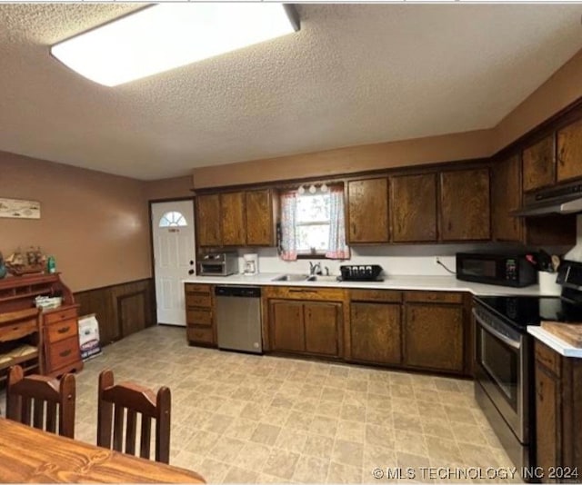 kitchen with dark brown cabinets, stainless steel appliances, a textured ceiling, and sink