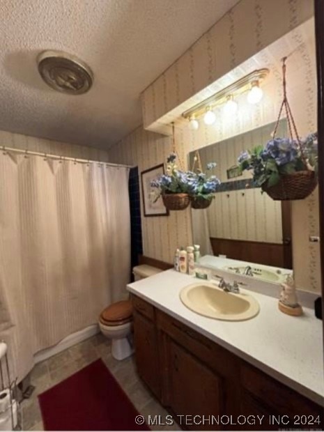 bathroom featuring a shower with shower curtain, vanity, toilet, and a textured ceiling