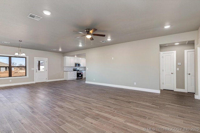 unfurnished living room featuring wood-type flooring and ceiling fan with notable chandelier