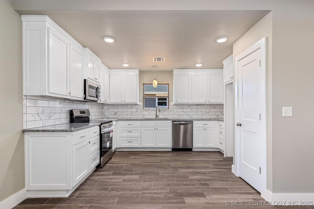 kitchen featuring sink, appliances with stainless steel finishes, white cabinetry, hanging light fixtures, and wood-type flooring