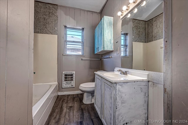 bathroom featuring vanity, toilet, a tub, heating unit, and hardwood / wood-style floors