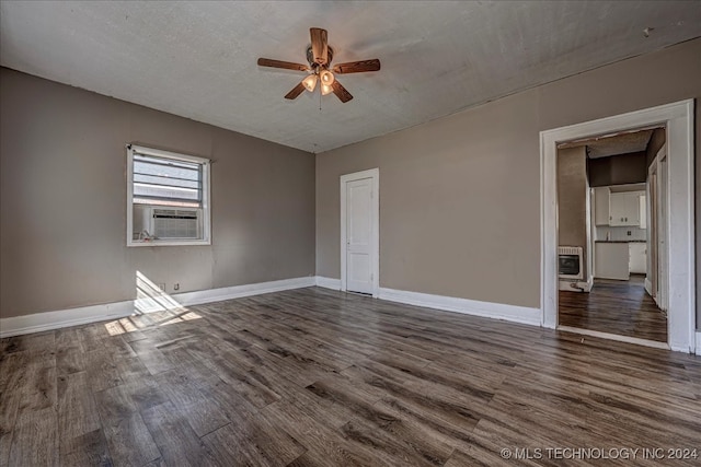 unfurnished room with ceiling fan, dark hardwood / wood-style floors, heating unit, cooling unit, and a textured ceiling