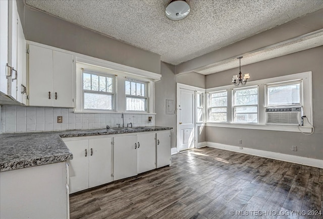 kitchen featuring dark hardwood / wood-style flooring, decorative light fixtures, sink, white cabinets, and a wealth of natural light